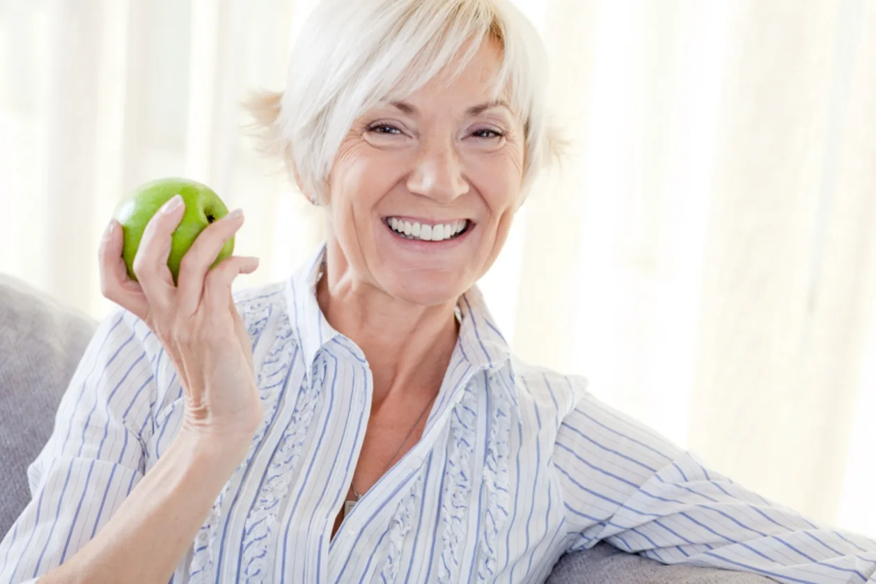 smiling mature woman eating apple as part of menopause morning routine